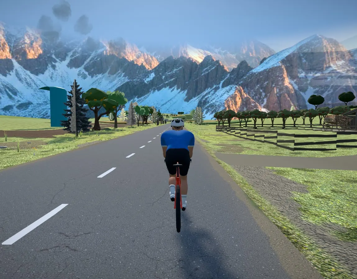 A rider in Cycloscape's 3D world riding a mountain road toward snow-capped peaks at sunset, past orchards and a farm